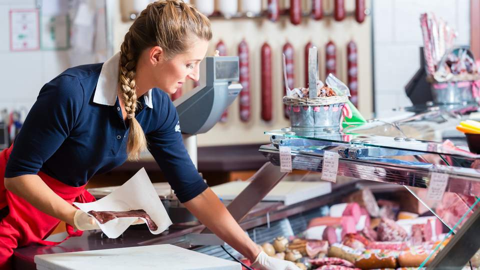 Vrouw aan het werk in een slagerij.